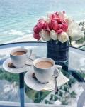 Две чашечки кофе и букет на фоне моря